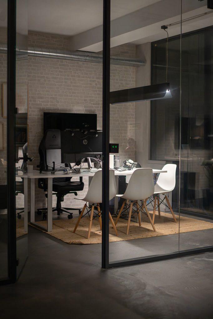 Escritório privado no Outglocal Coworking em Aveiro, com uma estação de trabalho multi-monitor e cadeiras de design brancas.